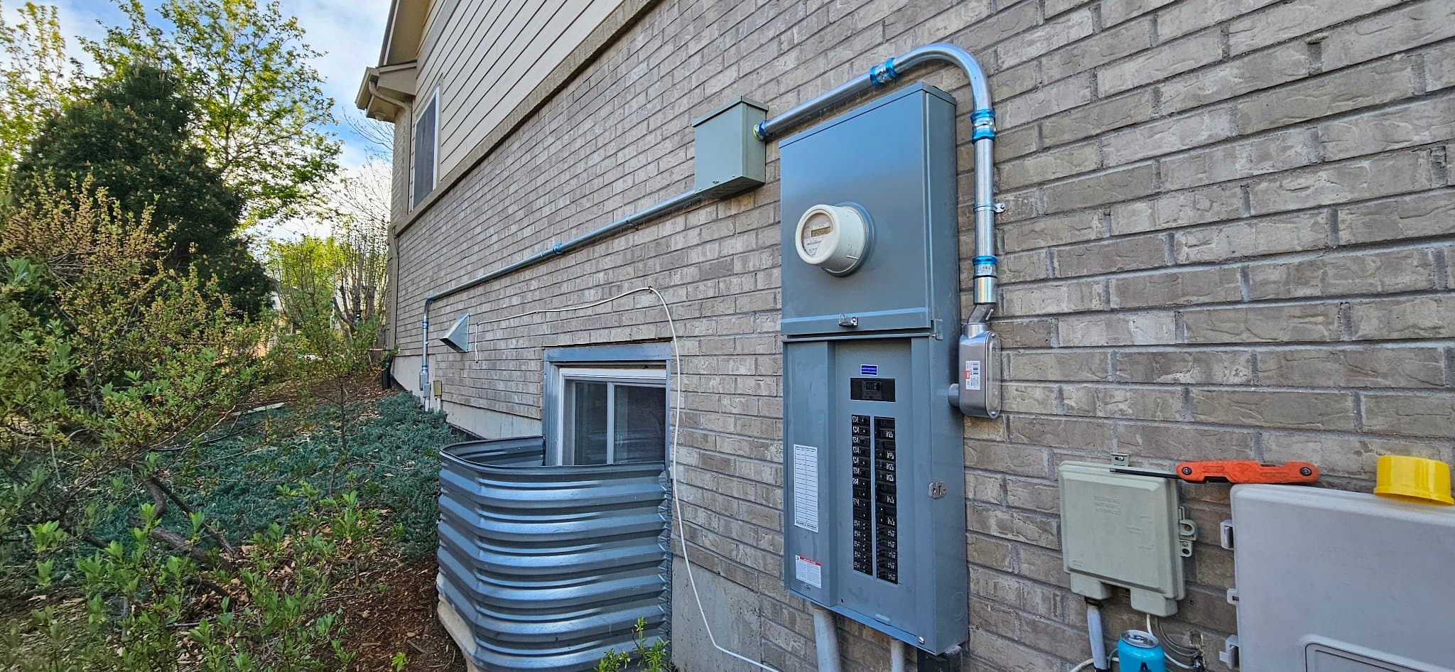 A finished 200A electrical panel and meter mounted on brick