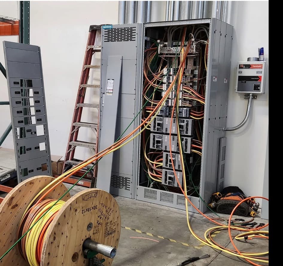 Electrician pulling service conductors into a panel